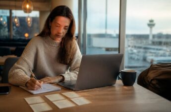 Iemand die op een checklist let tijdens het vergelijken van vakanties op een laptop