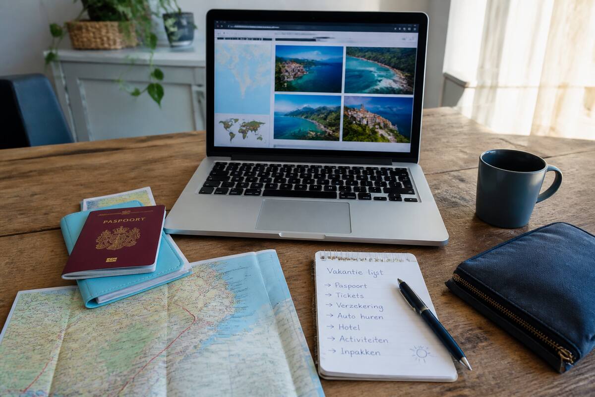 Praktische checklist op een bureau met reisdocumenten en een laptop voor vakanties vergelijken