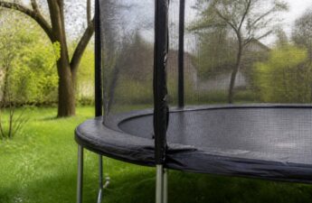 Trampoline onderhouden in de lente: frame en springmat in een tuin met natuurlijk licht